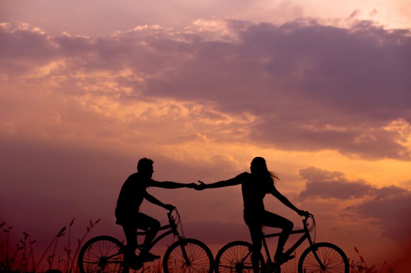 夕焼けのなか，仲良さそうに自転車で走る二人．