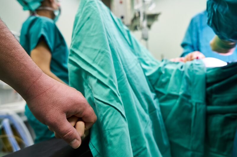 手術室で緊張する患者の手を握る
