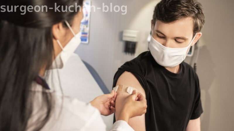 ワクチン接種して傷口にパッドを貼られる男性